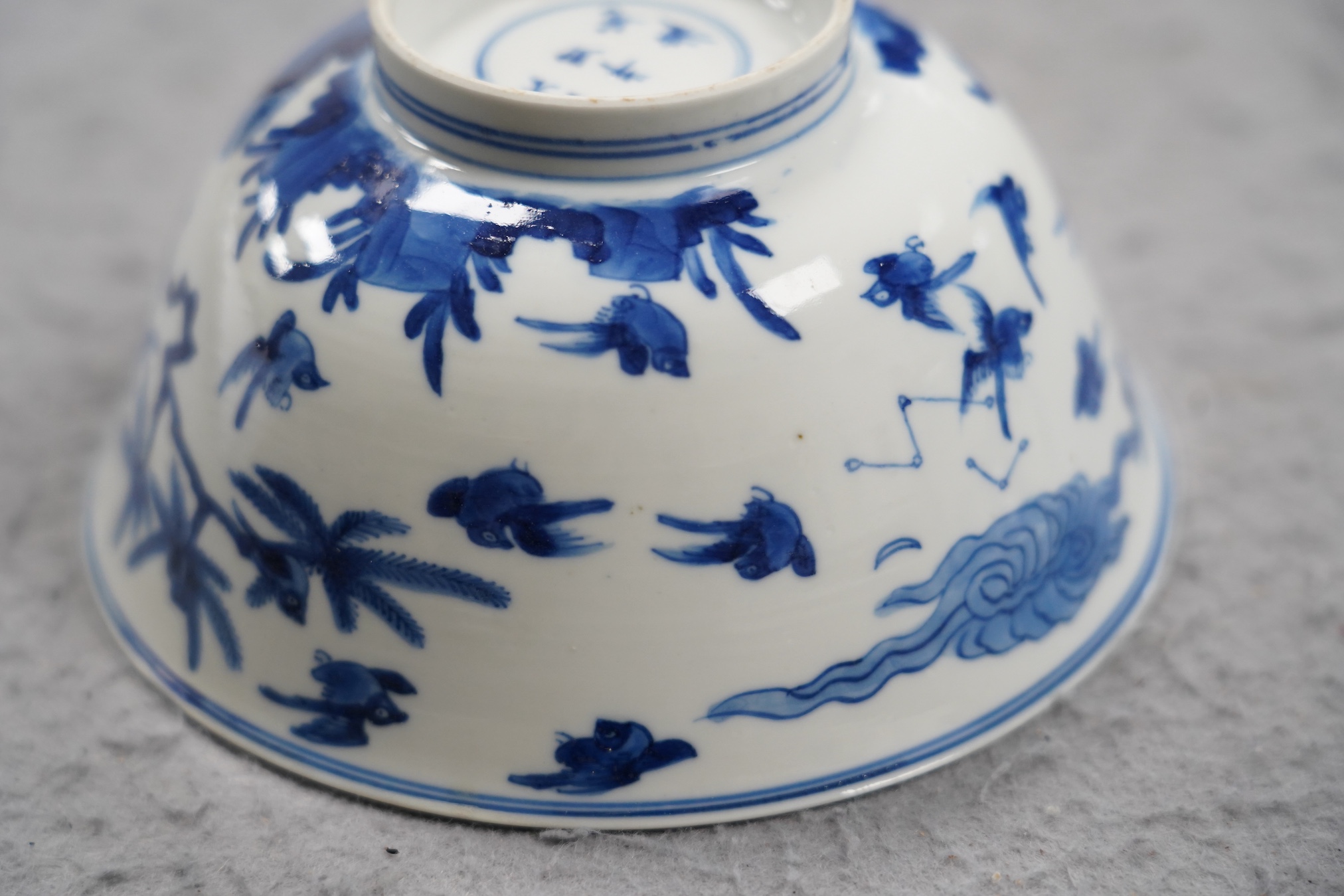 A near pair of Chinese blue and white ‘birds’ bowls, Kangxi period, one bowl restored